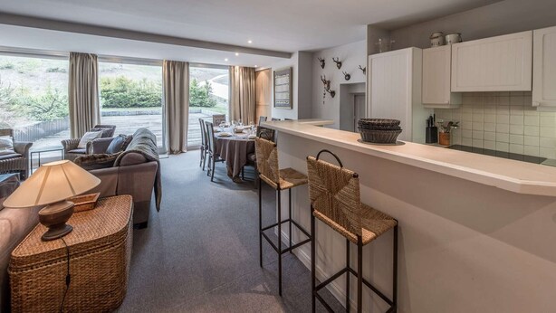 A modern kitchen with white cabinets, a dining area with a table and chairs, and a view of the outdoors. - Charming apartment in resort centre - 6 guests (Courchevel 1550)