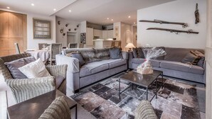 A modern living room with a sofa set, a dining table, and a kitchen in the background. - Charming apartment in resort centre - 6 guests (Courchevel 1550)