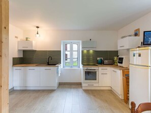 A compact kitchen with white cabinets, a sink, a stove, and a refrigerator. - House 5 min from Argelès-Gazost (Adast)