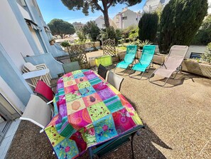 Un patio con un mantel colorido de patchwork, sillas de exterior y vistas de edificios circundantes.