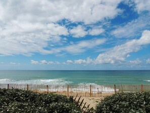 A beach with a wooden fence, clear sky, and ocean. - Biscarrosse: Charming Oceanfront Apartment (Biscarrosse)