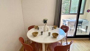 Een ronde eettafel met zes stoelen, een witte vaas met een plant, en diverse kommen en glazen op de tafel.
