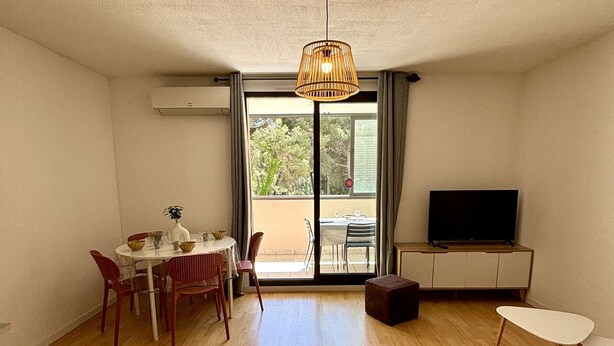 Een moderne woonkamer met een eethoek, een televisie en een groot raam.
