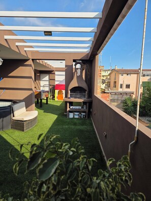 Een terras op het dak met kunstgras, een barbecue en een zithoek.