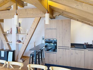 Eine moderne Küche mit Holzbalken, einem Essbereich mit Stühlen und einer schwarzen Arbeitsplatte.