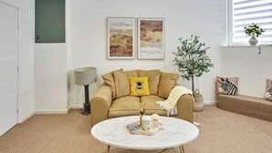 A living room with a sofa, a round coffee table, a lamp, and two framed pictures on the wall. - Boutique One Bed Apartment in Kemp Town (Brighton and Hove)
