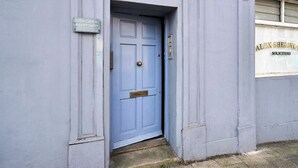 A blue door with a brass knocker, a sign reading 'Little Globe Apartments,' and a building with 'Alex Sherwood Solicitors' on the right. - Boutique One Bed Apartment in Kemp Town (Brighton and Hove)