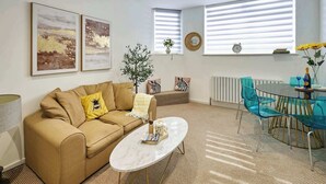 A living room with a sofa, coffee table, and a dining area with chairs and a table. - Boutique One Bed Apartment in Kemp Town (Brighton and Hove)