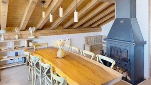 A dining area with a wooden table, chairs, hanging pendant lights, and a wood stove. - Spacious apartment, Mont Pourri view - 8 guests (Montvalezan-La Rosière)
