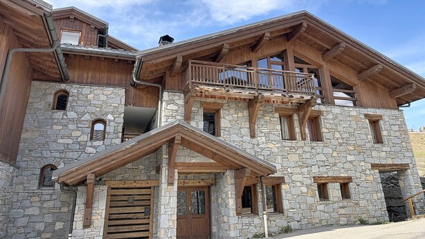 A multi-story stone building with wooden balconies, stone windows, and a stone entrance. - Spacious apartment, Mont Pourri view - 8 guests (Montvalezan-La Rosière)