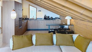 A cozy attic bedroom with a sofa, pillows, and a kitchen in the background. - Spacious apartment, Mont Pourri view - 8 guests (Montvalezan-La Rosière)