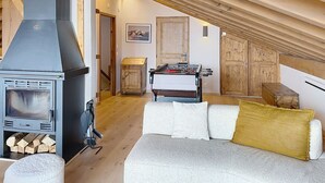 Acogedor dormitorio tipo loft con estufa de leña, mesa de fútbol y techo abovedado.