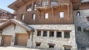 Un edificio de madera de varios pisos con paredes de piedra, balcones y una escalera de piedra.
