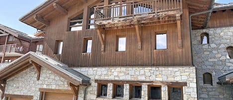 Un edificio de madera de varios pisos con paredes de piedra, balcones y una escalera de piedra.