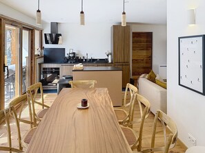 Eine moderne Küche mit Holzausstattung, einem Esstisch mit Stühlen und Pendelleuchten.