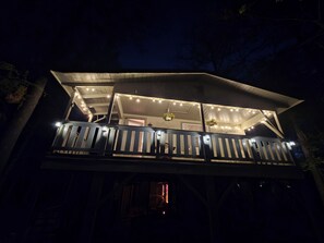 Ein zweistöckiges Gebäude mit Balkon, Lichterkette und hängenden Pflanzen.