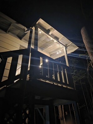 Eine mehrstöckige Holzkonstruktion mit Balkon, beleuchtet durch Deckenleuchten.