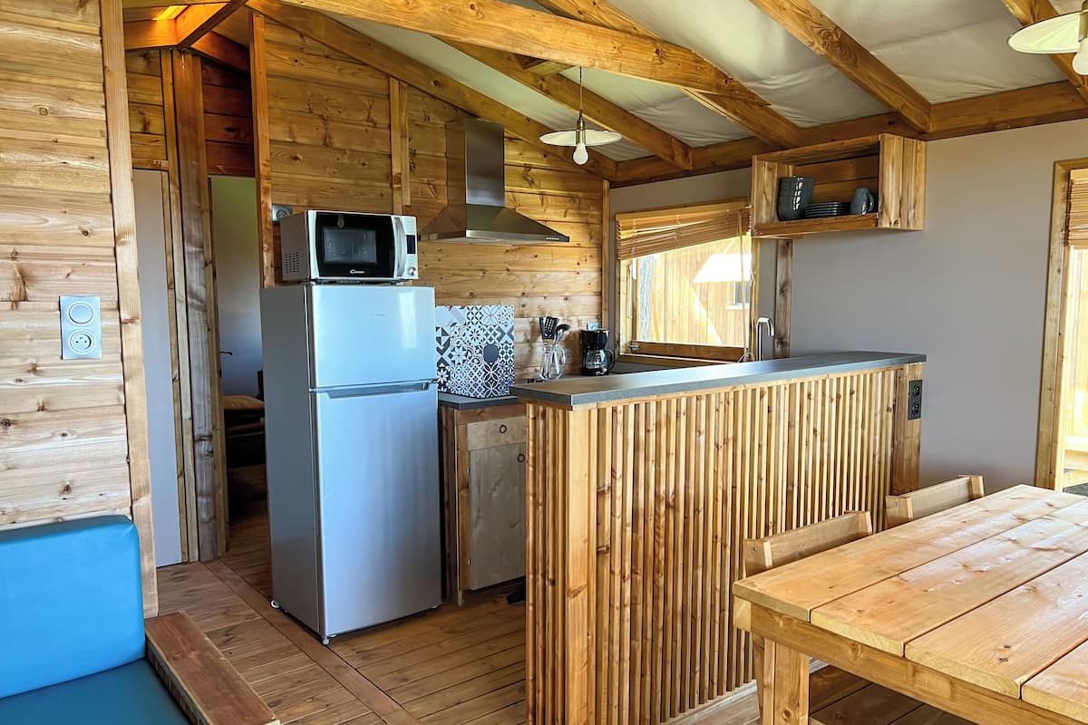 Una cocina compacta con microondas, refrigerador y encimera de madera.