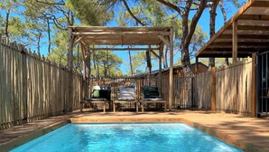 A wooden deck with a pool, lounge chairs, and a pergola. - La Tamarissière Village  (Agde)