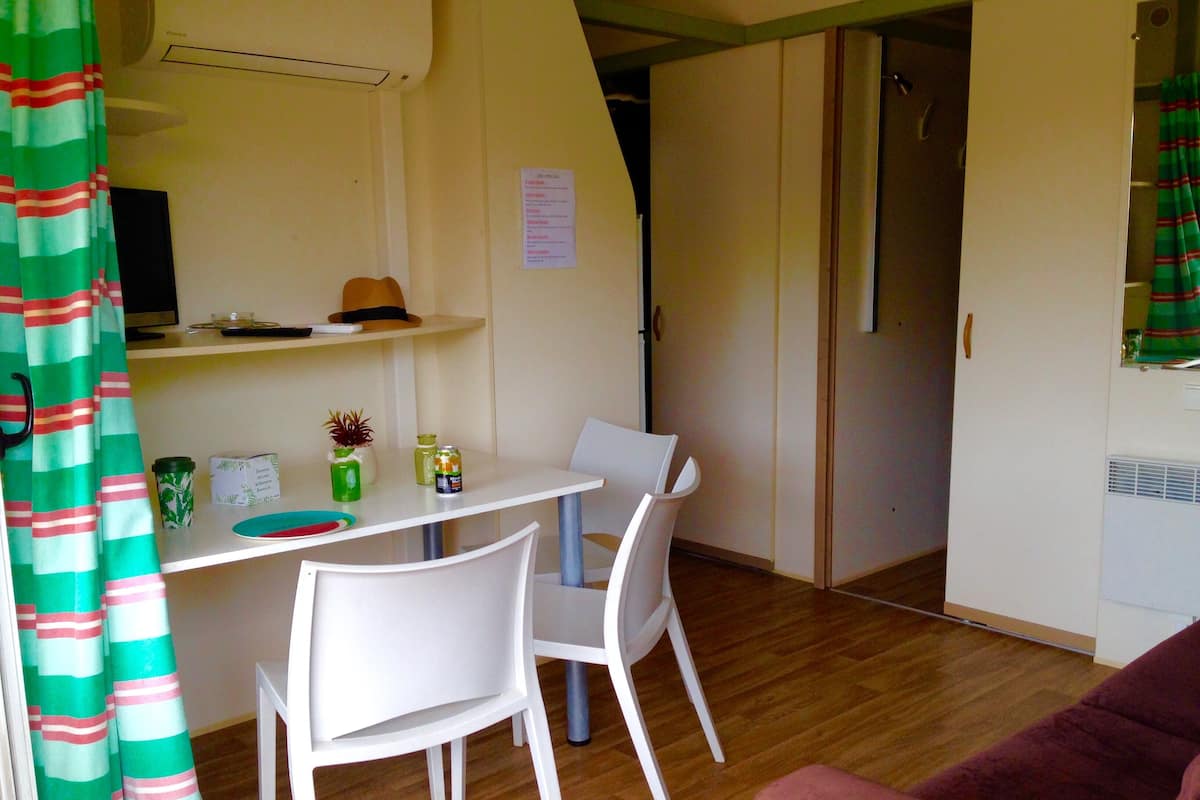 Un espacio habitable compacto con una mesa de comedor, dos sillas, un sofá y una zona de ducha.