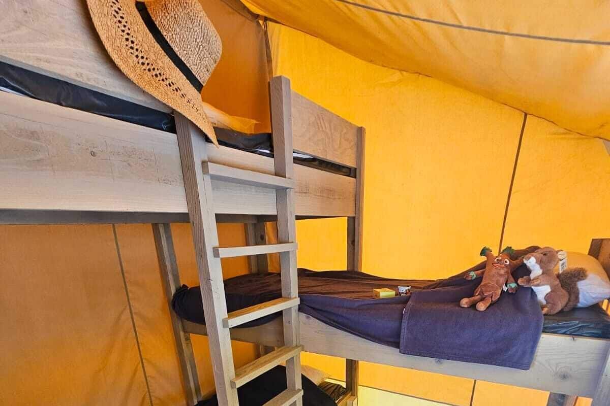 Una litera con escalera, un sombrero, juguetes de peluche y un flotador hinchable colorido.
