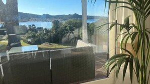 Quarto com grande janela dando para um lago e colinas.