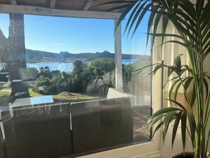 Ein Zimmer mit großem Fenster mit Blick auf einen See und Hügel.