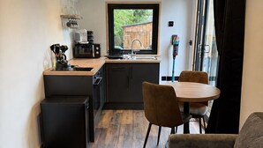 Een kleine keuken met een eethoek, een bank en een raam met gordijnen.