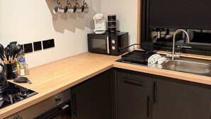 Een moderne keuken met een inbouwoven, een koffieapparaat, een spoelbak en een raam met jaloezieën.