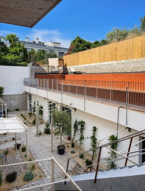 Une terrasse sur le toit, avec un mur en bois, une rambarde en métal et des plantes en pot.