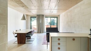 Une cuisine moderne dotée d’un grand îlot central, d’un coin repas avec une table et des chaises, et offrant une vue par une fenêtre.