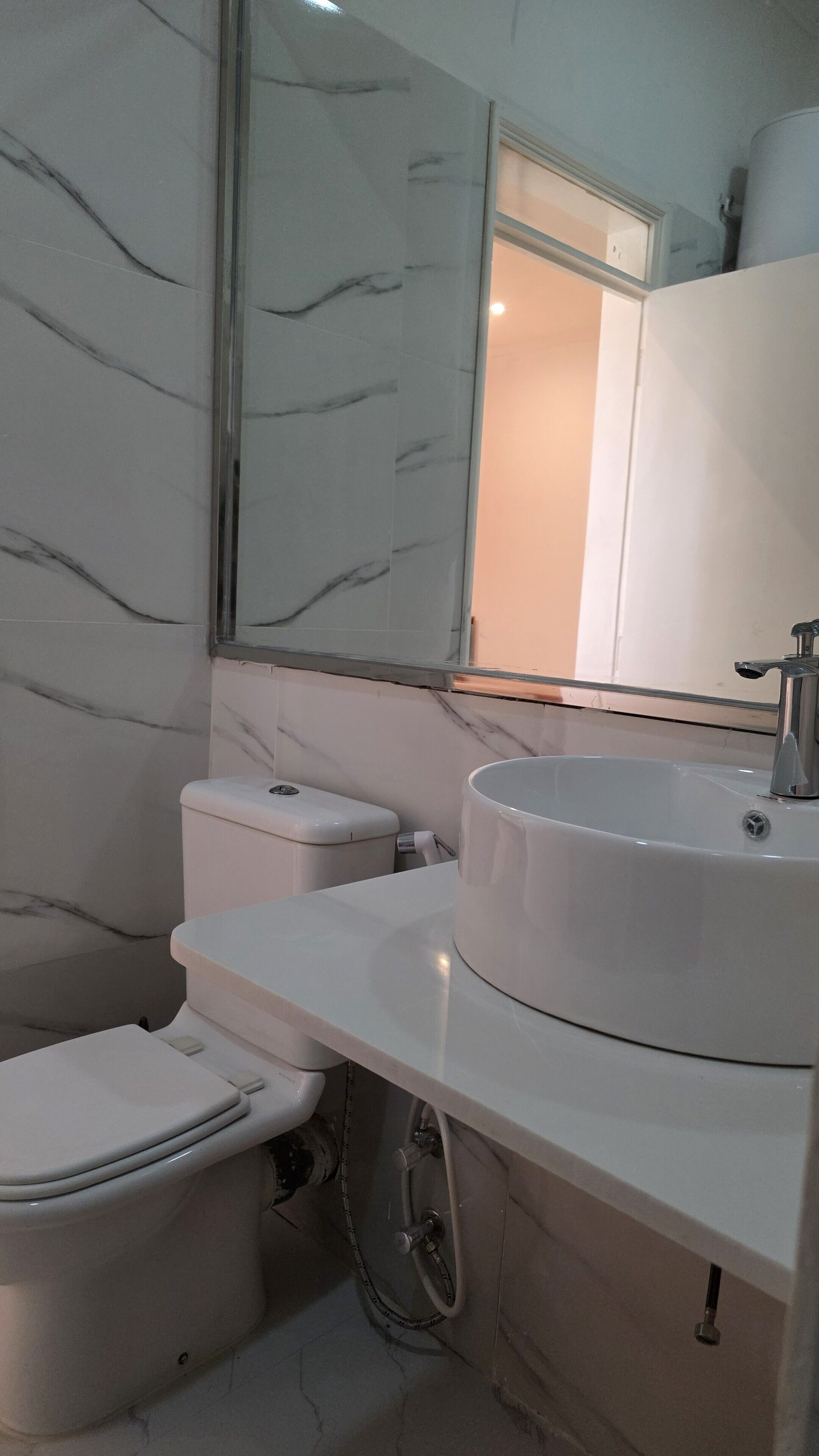 Un baño con inodoro, lavamanos y espejo.