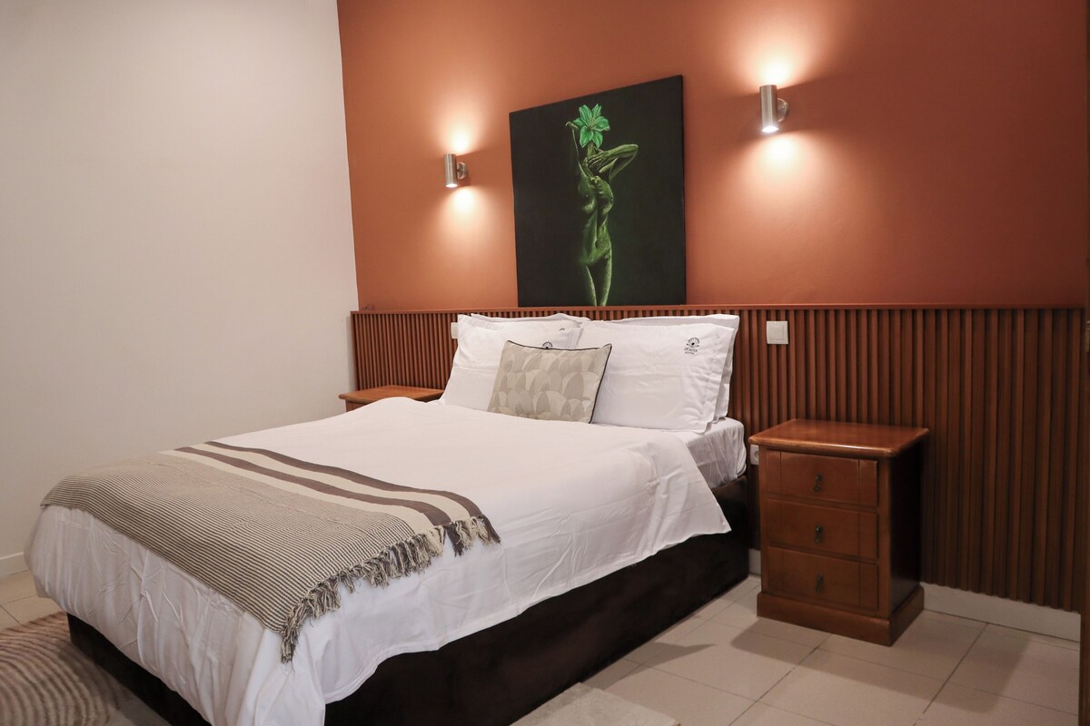 A bedroom with a bed, bedside tables, and a wall-mounted artwork.