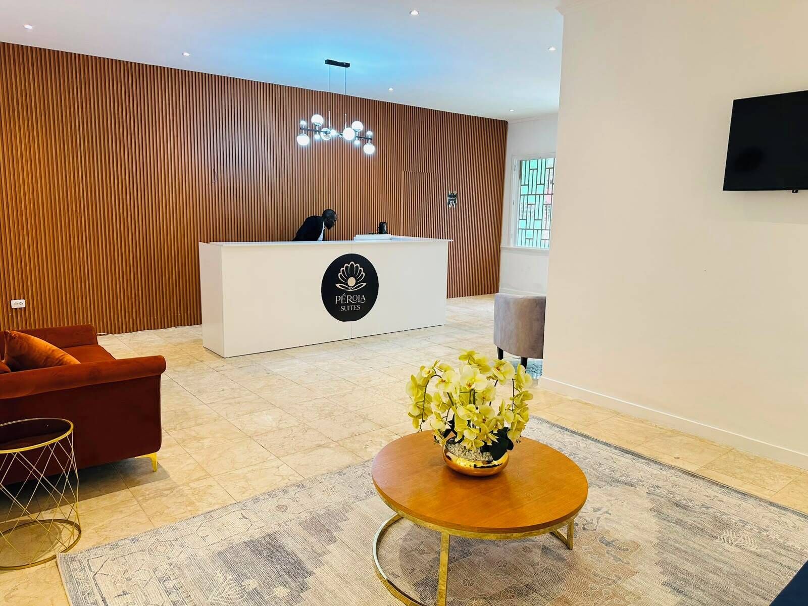 Een hotel receptie met een receptiebalie, een bank, een bijzettafeltje en een sierplant.