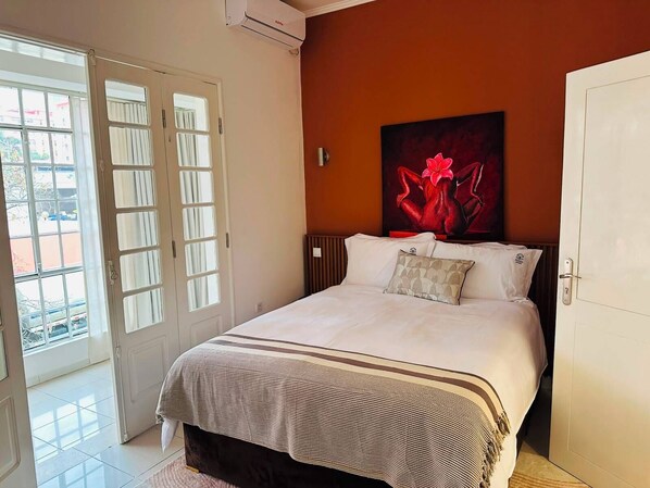 A hotel room with a bed, a door, and a window.