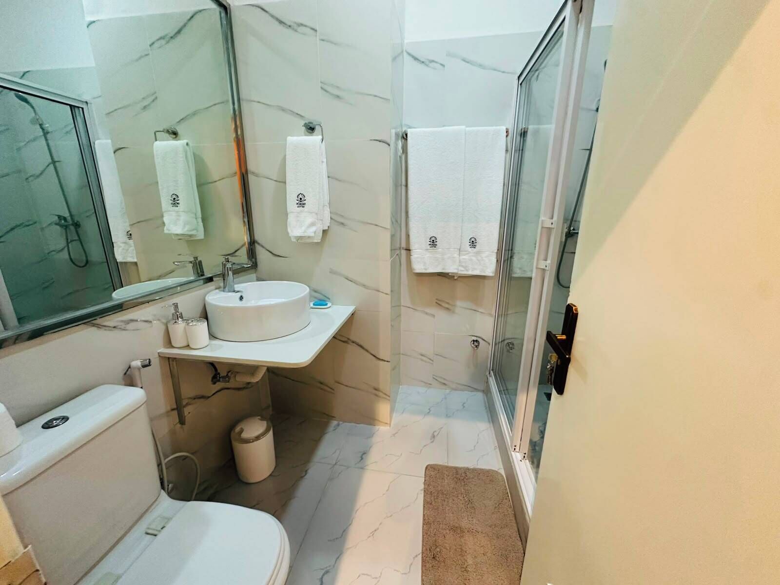 A bathroom with a toilet, sink, mirror, and shower area.