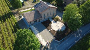 An aerial view of a building with a tiled roof, a circular courtyard with seating, and a paved driveway. - Agriturismo Ca' Brusca (Reggio nell'Emilia)