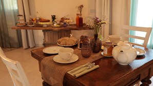 A dining table set with plates, cups, utensils, a teapot, and a vase with flowers. - Agriturismo Ca' Brusca (Reggio nell'Emilia)