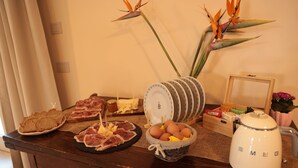 A breakfast setup with bread, meats, eggs, and a coffee maker on a wooden table. - Agriturismo Ca' Brusca (Reggio nell'Emilia)