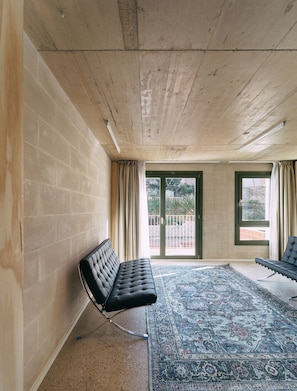 A room with a bench, a patterned rug, and a view through a glass door. - Mooeve Montjuïc - One bedroom Unit (Barcelona)