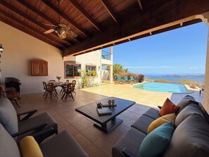 Eine Terrassenanlage im Freien mit Pool, Sitzgelegenheiten und Meerblick.