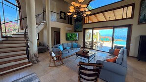A spacious living area with a staircase, a large sofa, a coffee table, and a view of the ocean. - Oceanview Luxury Villa in Playa Hermosa | 4 BR - 4.5 Baths & Private Pool (Playa Hermosa)