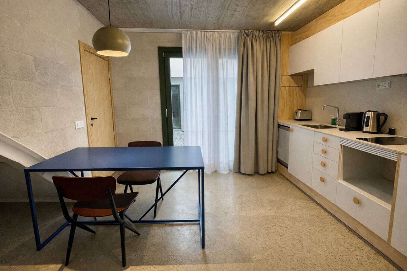 A compact kitchen with a dining table and chairs, a built-in oven, and a sink.