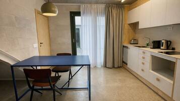 A compact kitchen with a dining table and chairs, a built-in oven, and a sink.