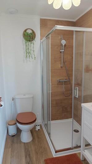 A modern bathroom with a glass-enclosed shower, a toilet, and a sink. - defaultName (Songeons)