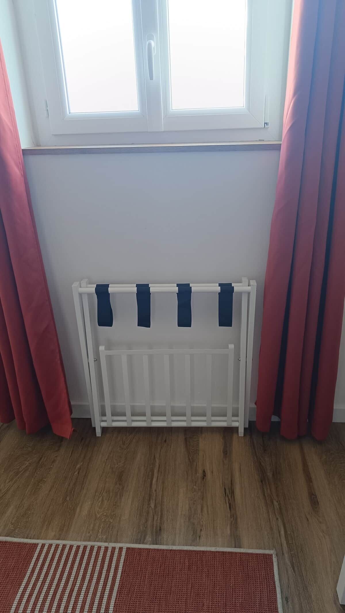 Una stanza con termosifone bianco, tende rosse e pavimento in legno.