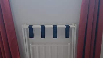 Una stanza con termosifone bianco, tende rosse e pavimento in legno.