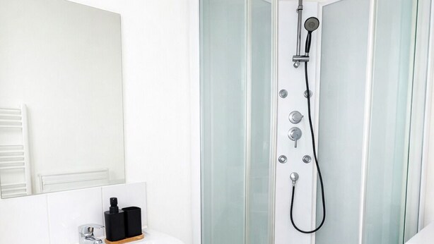 A modern bathroom with a glass-enclosed shower, a white sink, and a washing machine.