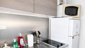 A kitchen with a stainless steel sink, white cabinets, a microwave, and a refrigerator.