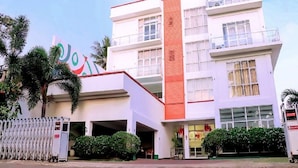 A multi-story hotel with a prominent entrance, a vertical red accent wall, and a sign with a logo.